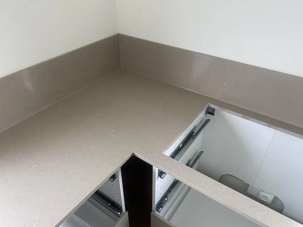 Köksbänkskiva i Silestone Coral Clay med uppvikt stänkkant i hörnet av ett kök i Vellinge.