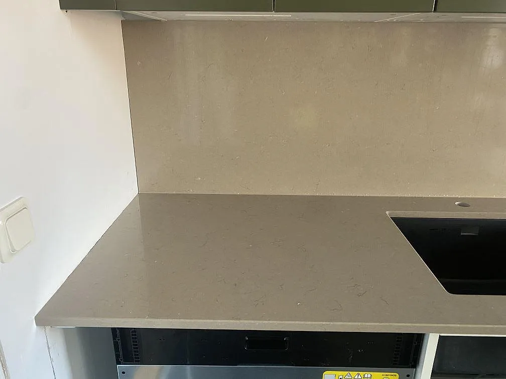Hörnparti av köksbänkskiva i Silestone Coral Clay med underlimmad diskho och stänkskydd i greige komposit i Vellinge.