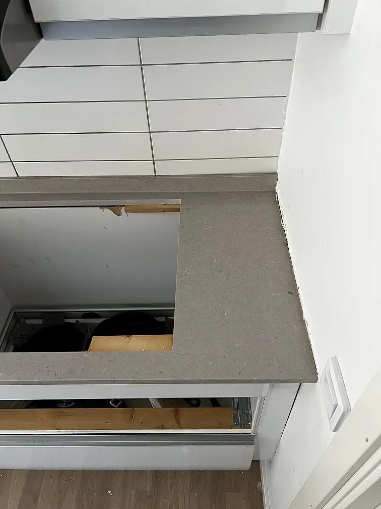 Stensida i greige Silestone Coral Clay mot vit kakel i ett kök under montering i Vellinge.