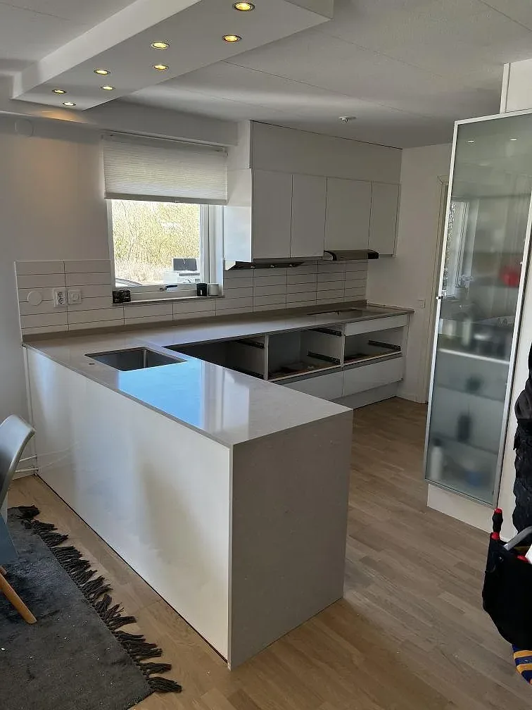 Köksbänkskiva och köksö i Silestone Coral Clay, polerad greige kvartskomposit, i ett kök under montering i Vellinge.