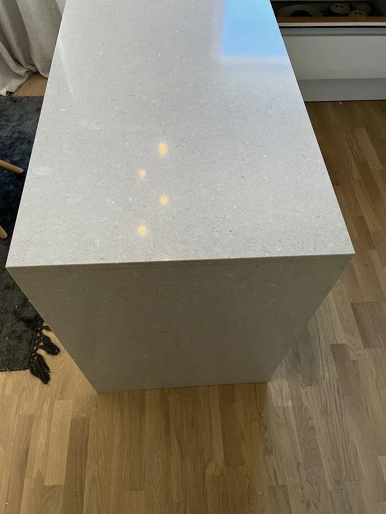 Polerad köksö i Silestone Coral Clay med greige ton som speglar takspottar, i ett kök i Vellinge.