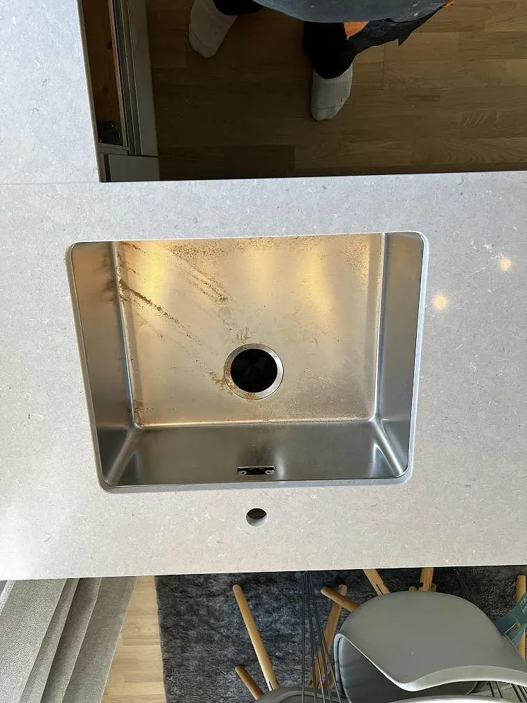 Underlimmad rostfri diskho med separat hål för blandare och tvålpump i en köksö av Silestone Coral Clay i Vellinge.