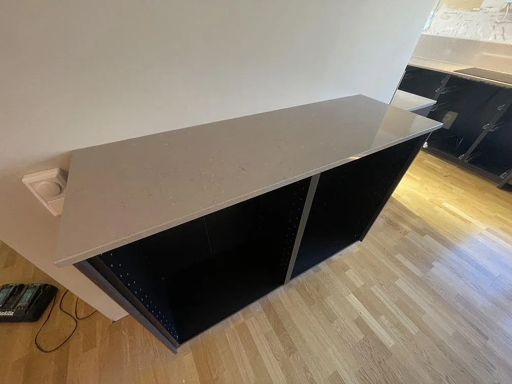 Köksbänkskiva i varm beige Silestone Coral Clay, polerad, monterad på köksstommar med synlig hörnurtagning i ett kök i Vendelsö.