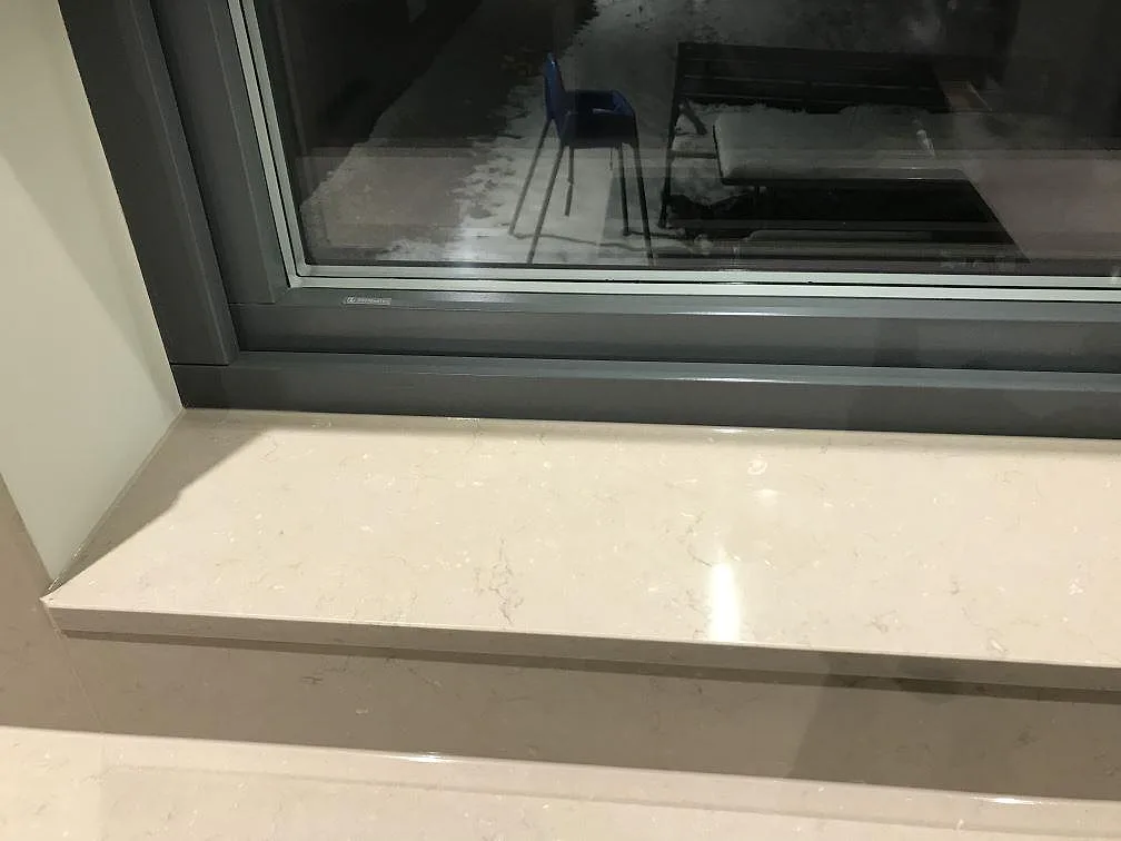 Fönsterbänk i polerad Silestone Coral Clay som möter bänkskivan i samma sten i ett kök i Vrigstad.