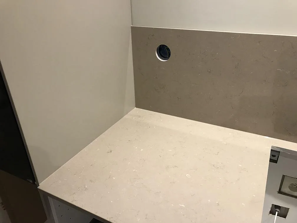 Bänkskiva i Silestone Coral Clay med uppvikt stänkskydd i samma sten och uttagshål i ett kök i Vrigstad.