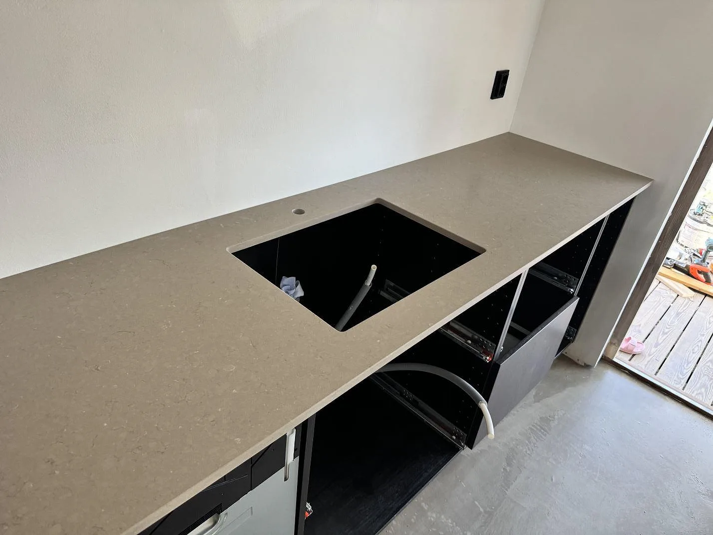 Rak köksbänkskiva i 20 mm Silestone Coral Clay, Mocka, med rektangulärt urtag och svart stomme under montering i Ystad.