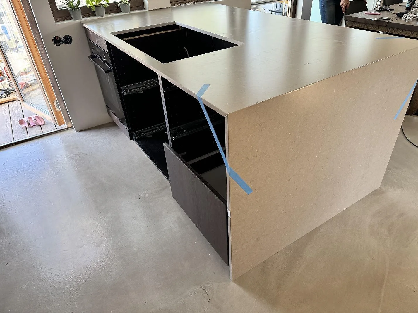 Köksbänkskiva i gråbeige Silestone Coral Clay, Mocka, med skivsida och rektangulärt urtag under montering i Ystad.