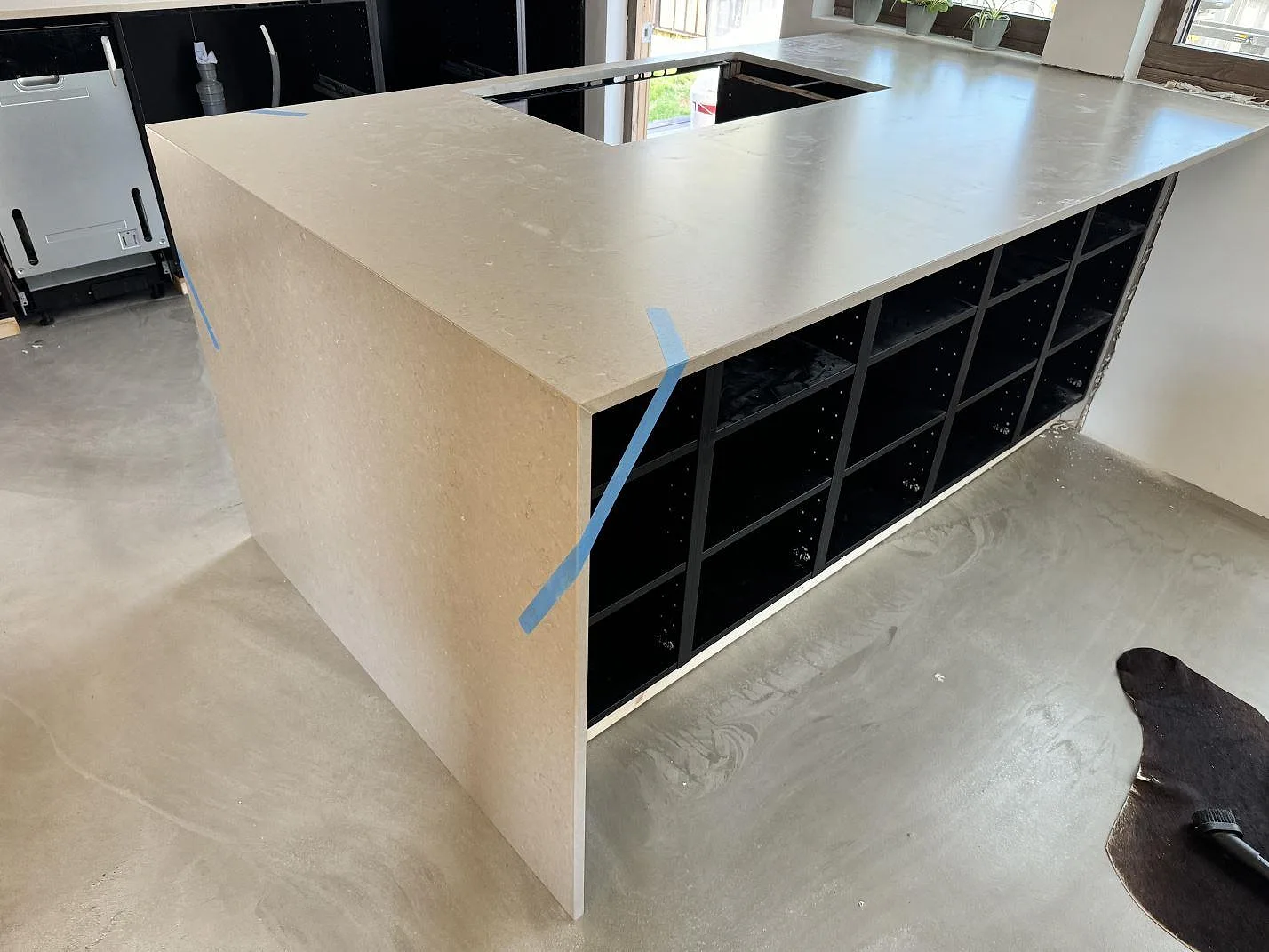 Sammanhängande köksbänkskiva i Silestone Coral Clay, Mocka, med gråbeige skivsida och öppna köksstommar i Ystad.