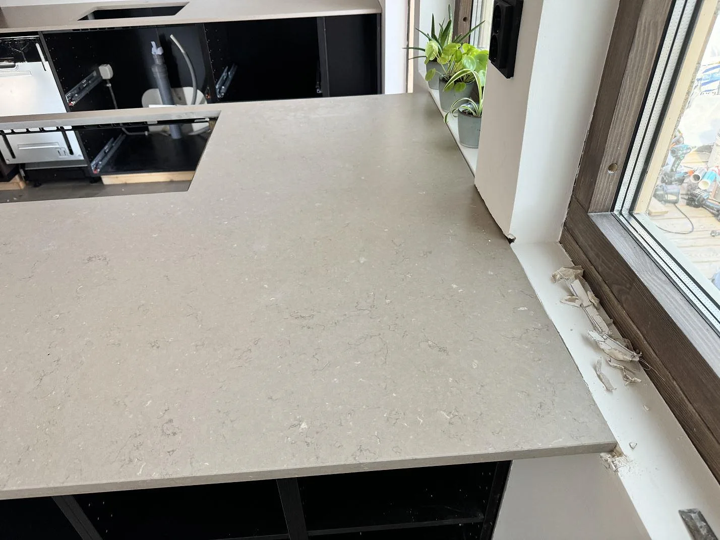 Detalj av Silestone Coral Clay, Mocka, som bred köksbänkskiva vid fönster med gråbeige mineralmönster i Ystad.