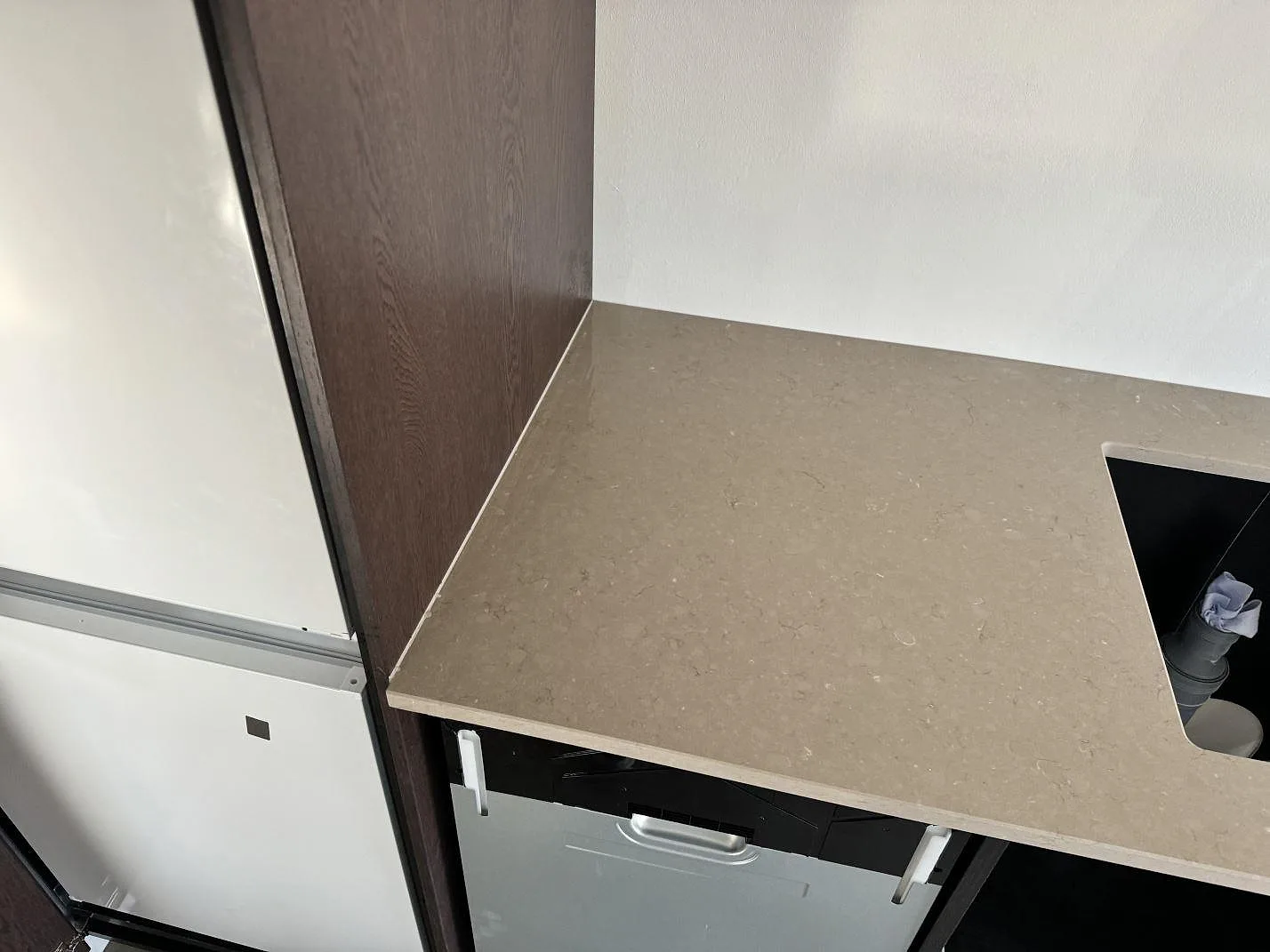 Närbild av matt Silestone Coral Clay som köksbänkskiva med gråbeige komposityta och urtag vid vägg i Ystad.