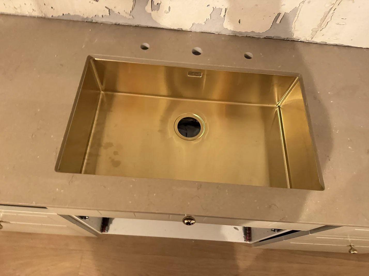 Närbild på guldfärgad diskho i polerad Silestone Coral Clay-komposit med förborrade hål i Ystad.