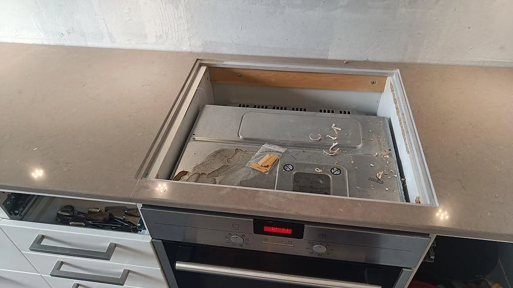 Hällöppning i polerad Silestone Coral Clay ovanför ugnen i ett kök under montering i Ytterby.