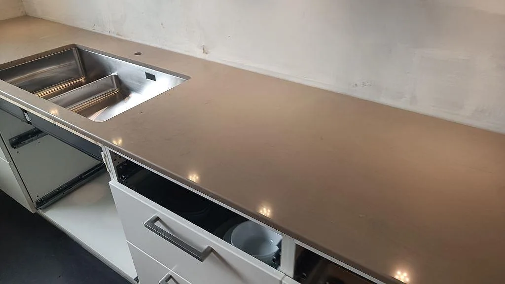 Polerad köksbänkskiva i Silestone Coral Clay med rostfri diskho och lång arbetsyta mot vägg i Ytterby.