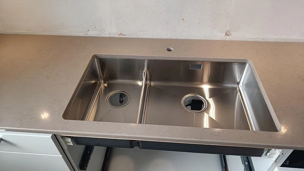 Närbild på rostfri diskho i polerad Silestone Coral Clay i köket i Ytterby.