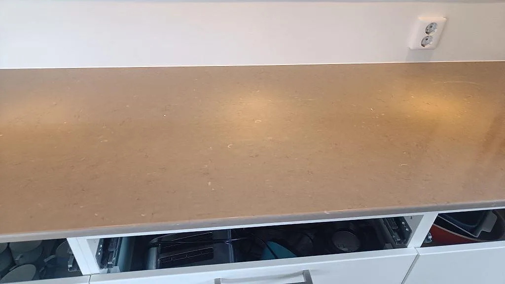 Detalj av polerad Silestone Coral Clay på sidobänk med öppen lådrad i köket i Ytterby.