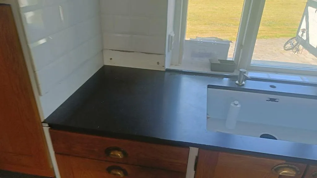 Närbild av diskzonen med mörk Silestone Corktown, Mocka, vit underlimmad diskho och kaklad vägg i Blentarp.