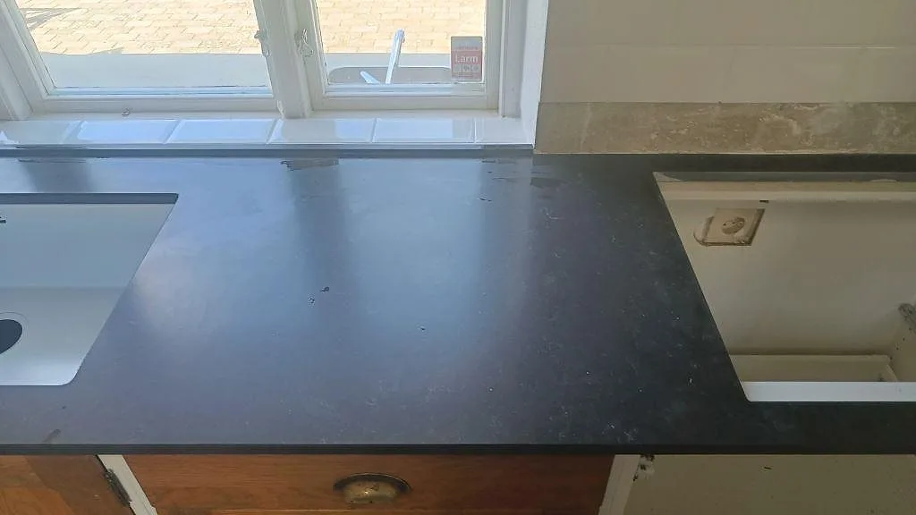Köksbänkskiva i Silestone Corktown, Mocka, med diskho och hällurtag längs fönsterväggen i Blentarp.