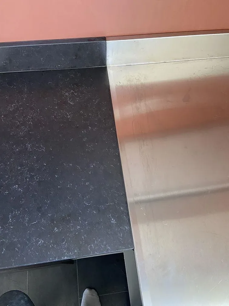 Närbild på den matta, mörkbruna ytan i Silestone Corktown köksbänkskiva mot ett rostfritt stänkskydd i Gråbo.