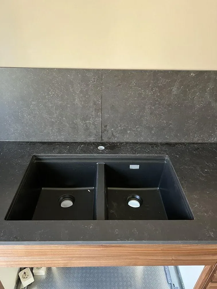 Köksbänkskiva i Silestone Corktown med svart dubbelho och mörkt stänkskydd i Lomma.