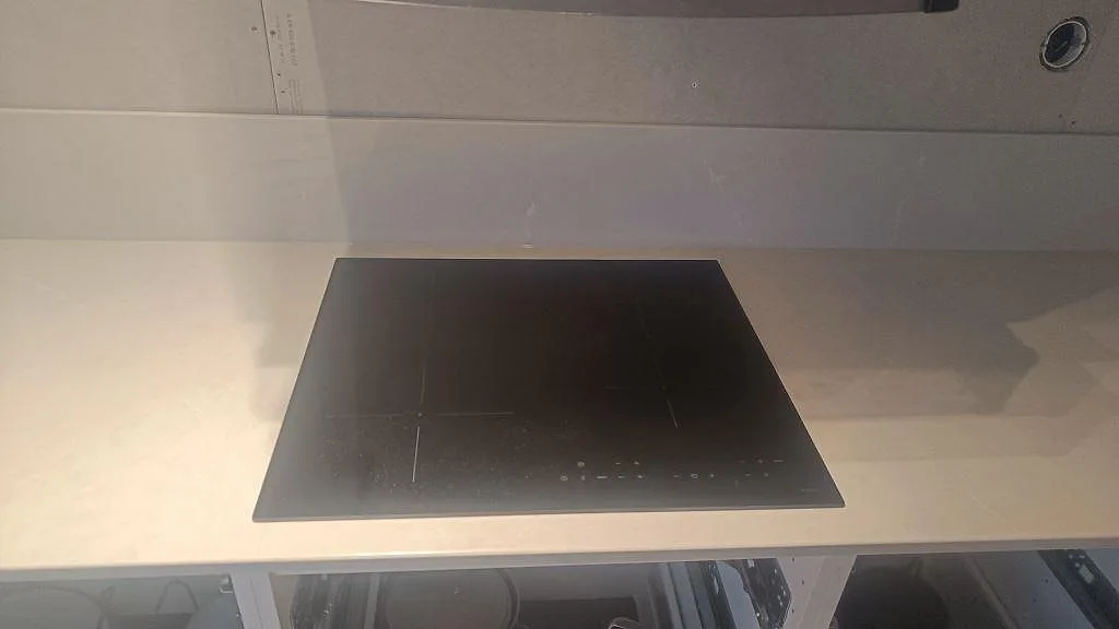 Svart häll monterad i polerad Silestone Desert Silver med ljus komposityta och stänkkant i Ängelholm.