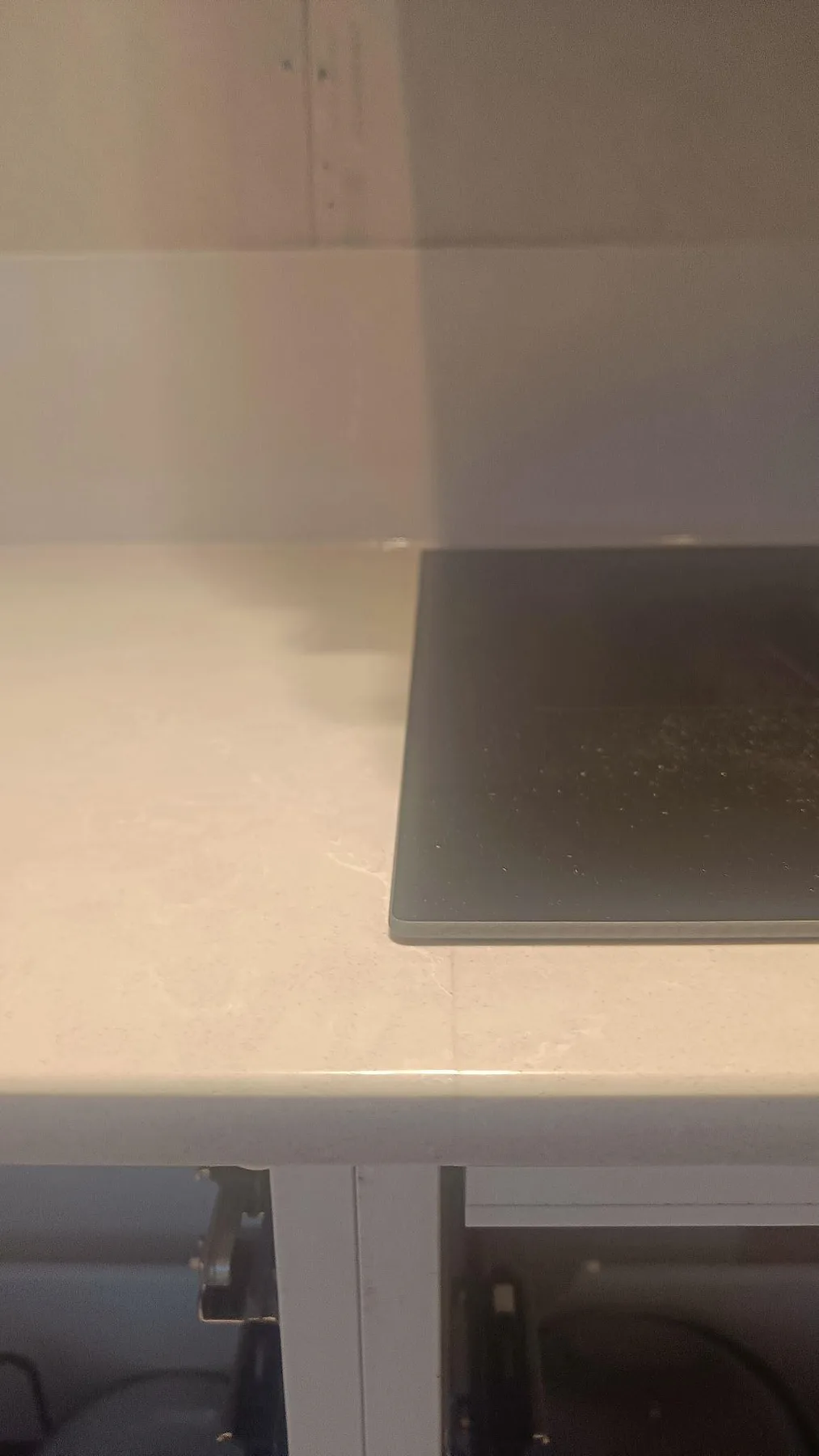 Vertikal detalj av polerad Silestone Desert Silver med svart häll, framkant och vita köksstommar i Ängelholm.