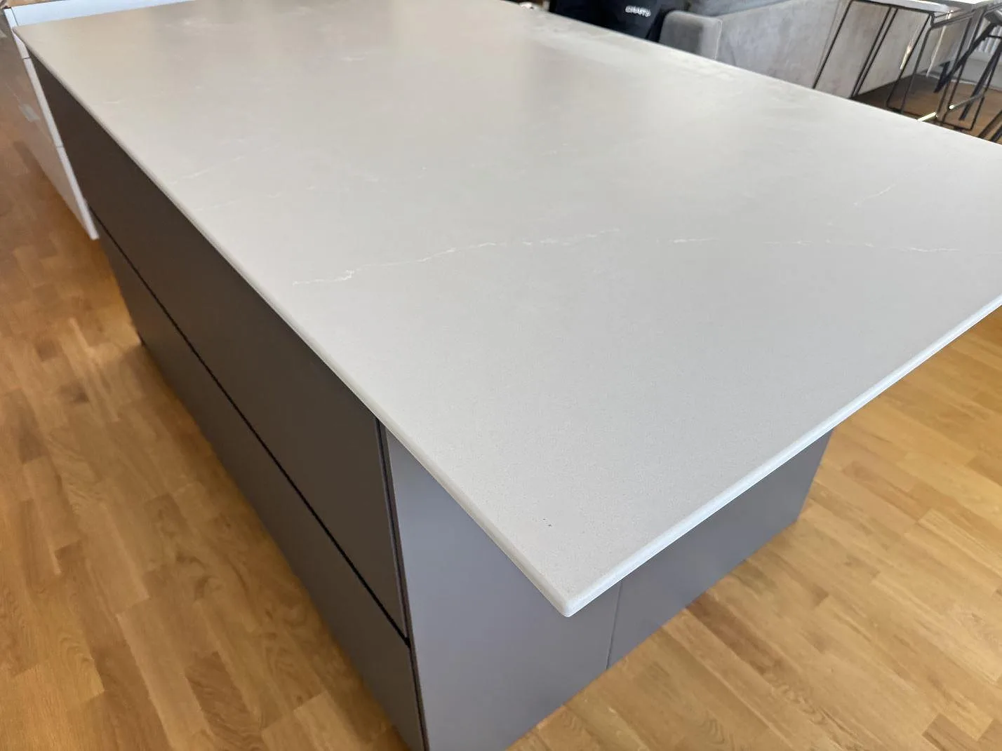 Lång vy längs köksön med 12 mm Silestone Desert Silver kvartskomposit i matt Mocka, ljus ådring och mörkgrå stommar i Alingsås.