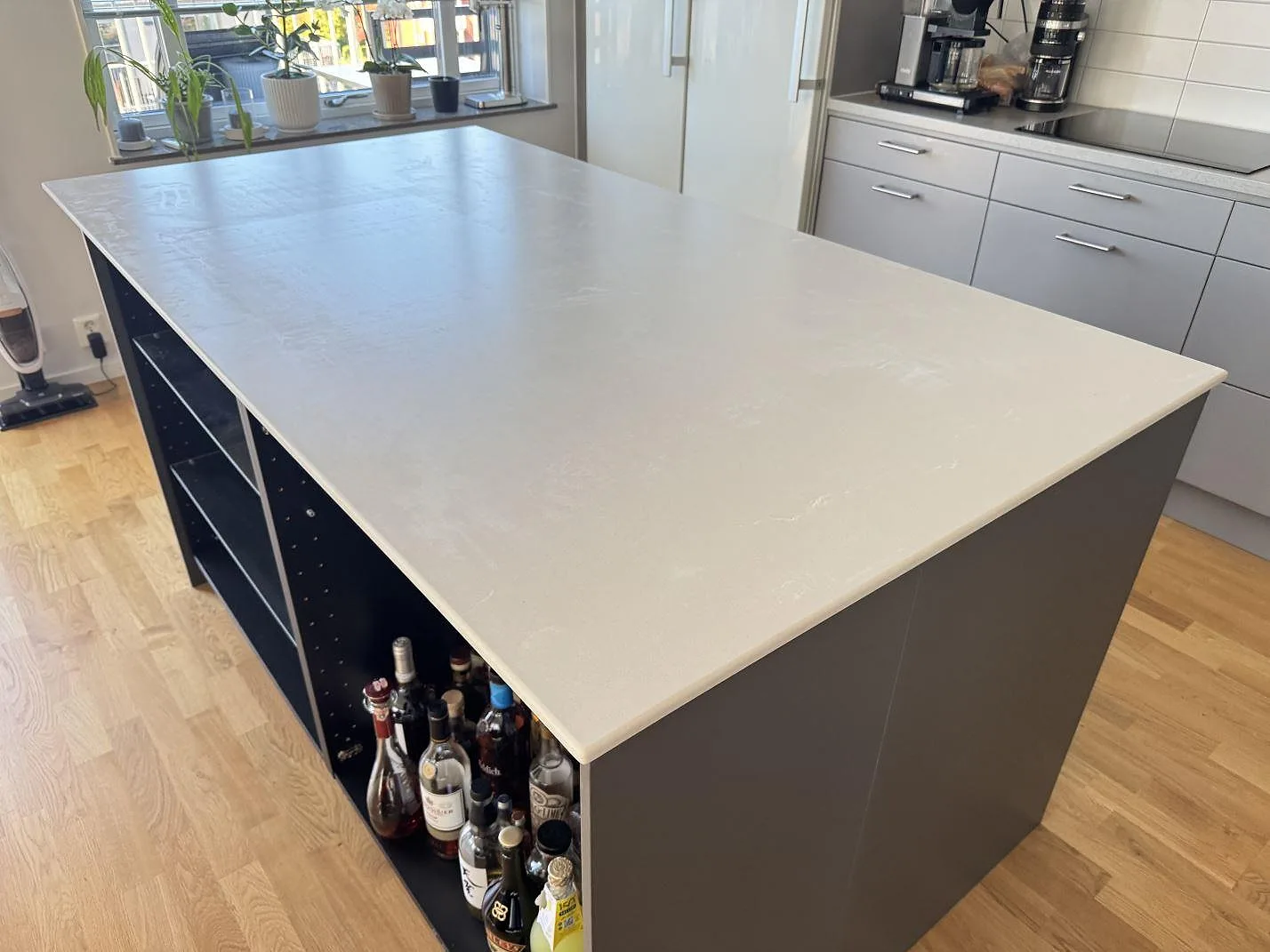 Bänkskiva på köksö i Silestone Desert Silver kvartskomposit, matt Mocka, med tunn kant och ljus ådring i ett kök i Alingsås.