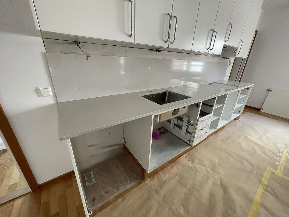 Köksbänkskiva i polerad Silestone Desert Silver, 20 mm komposit, med rostfri diskho och stänkskydd i ett kök i Eskilstuna.