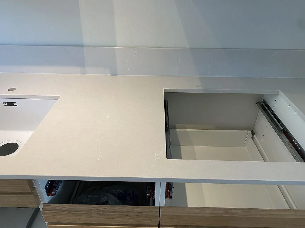 Polerad Silestone Desert Silver som köksbänkskiva med uppvikt stänkkant, synliga öppningar och träfronter i Halmstad.