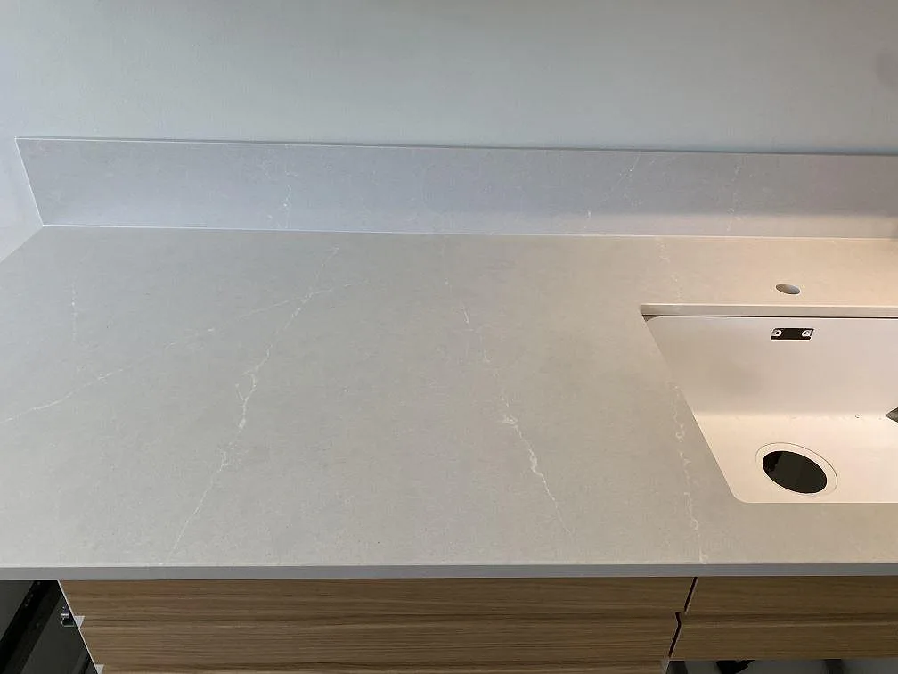 Närbild på 12 mm Silestone Desert Silver med diskhoområde, polerad yta och diskret ådring mot träinredning i Halmstad.