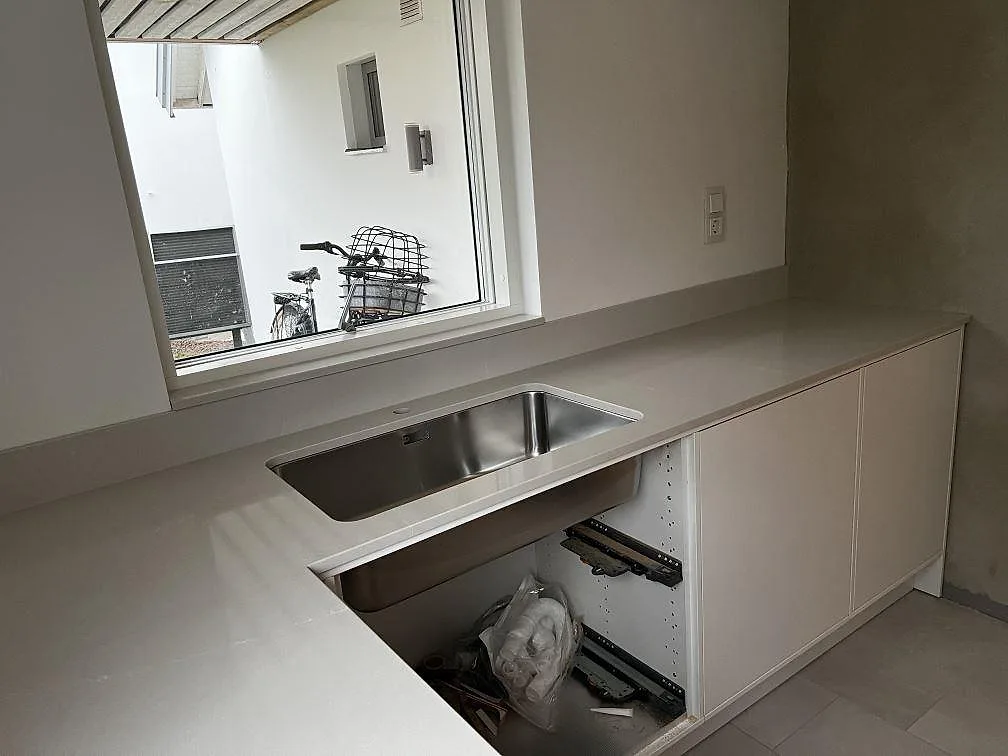 Köksbänkskiva i polerad Silestone Desert Silver komposit med underlimmad rostfri diskho och fönster i Halmstad.