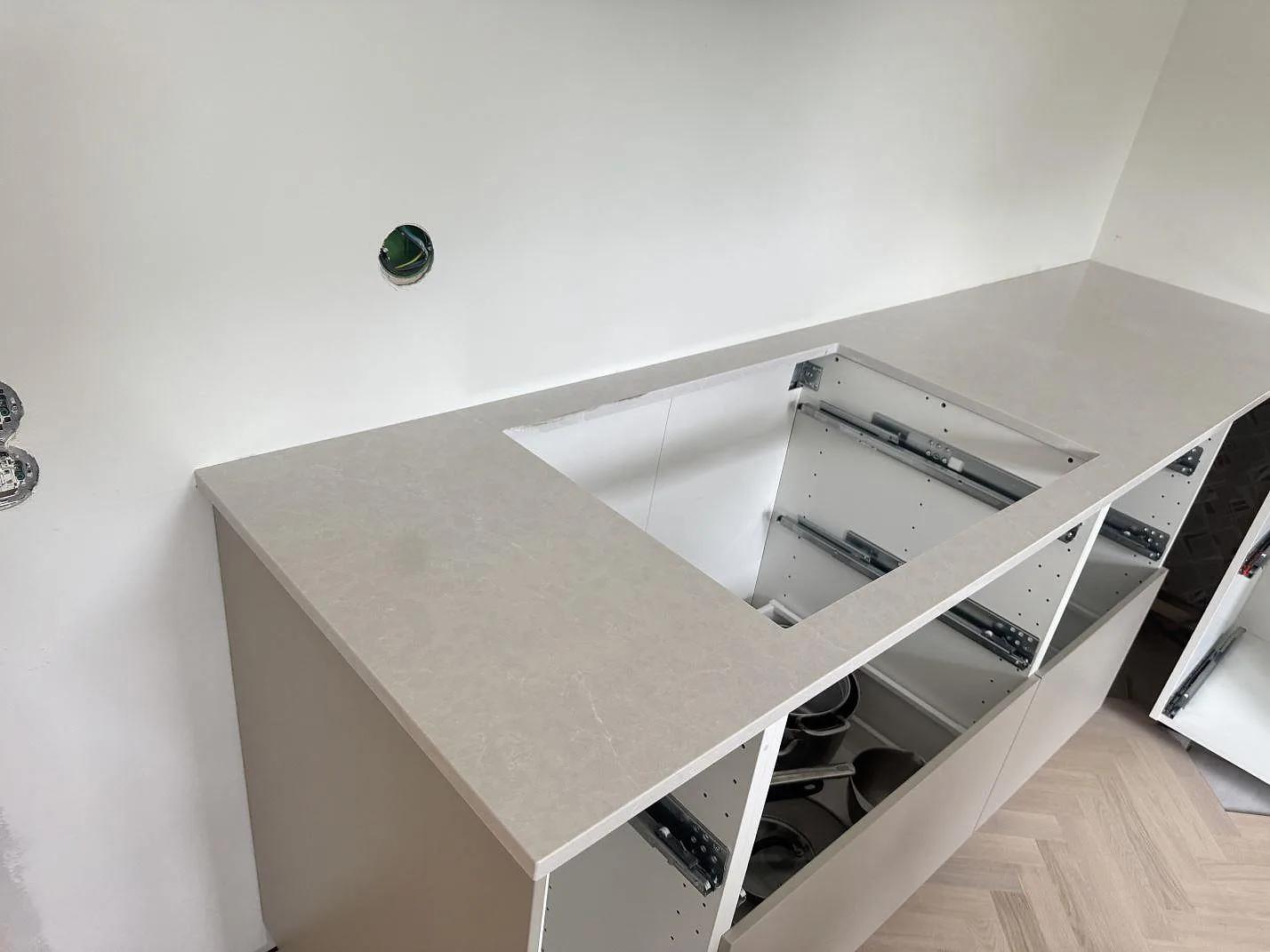 Köksbänkskiva i polerad Silestone Desert Silver med förberett hälluttag och låg stänkkant i ett kök i Halmstad.