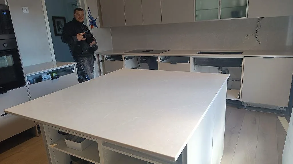 Köksbänkskiva och stort köksö i Silestone Desert Silver, varmgrå kvartskomposit med matt yta, i ett kök under montering i Helsingborg.