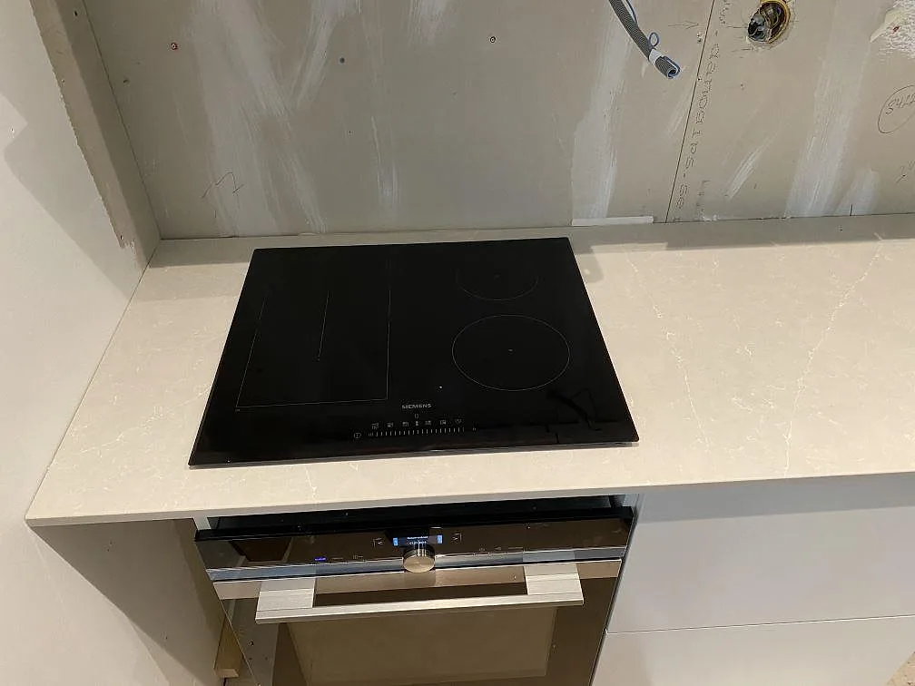 Svart häll infälld i en ljus polerad Silestone Desert Silver köksbänkskiva i Höllviken.