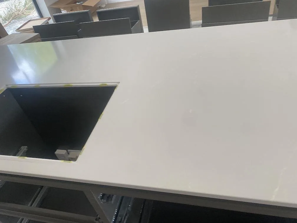 Detalj av ljus polerad Silestone Desert Silver med hällurtag på en köksö under montering i Höllviken.