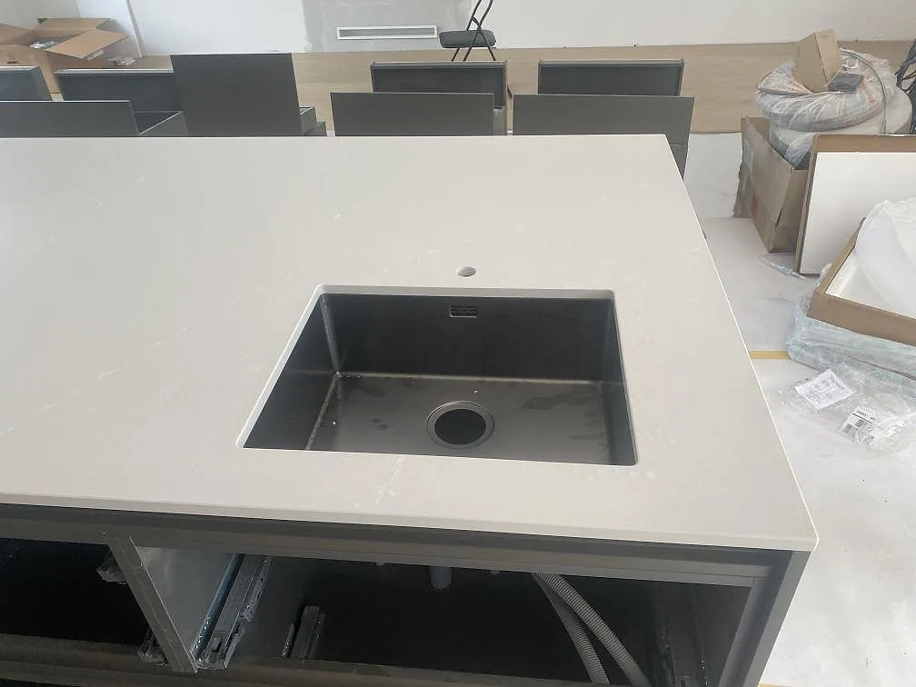 Närbild på underlimmad rostfri diskho i polerad Silestone Desert Silver på köksön i Höllviken.