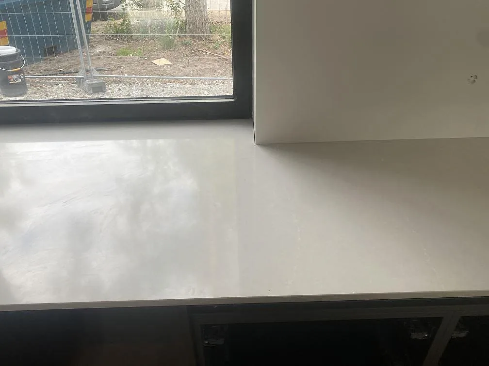 Bänkparti i polerad Silestone Desert Silver vid fönster med ljus ådring och öppna stommar i Höllviken.