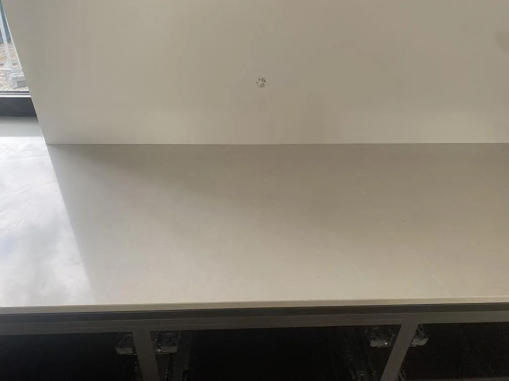 Rak bänkyta i polerad Silestone Desert Silver monterad mot vägg i ett kök under arbete i Höllviken.