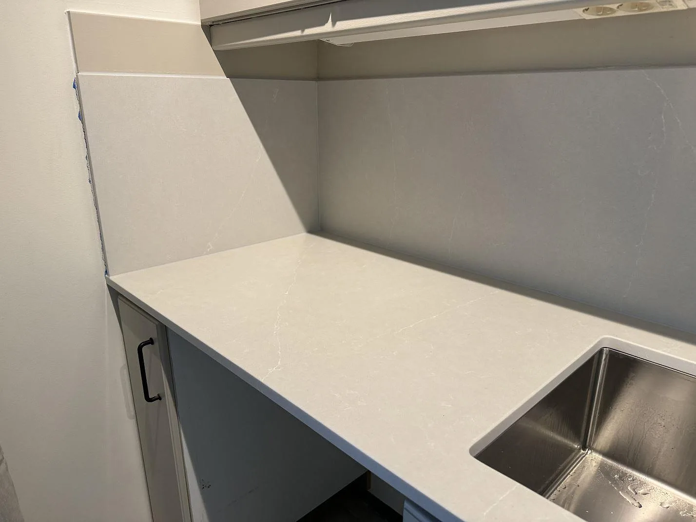 Köksbänkskiva i ljus Silestone Desert Silver, Mocka, med underlimmad rostfri diskho och väggbeklädnad i Hovås.