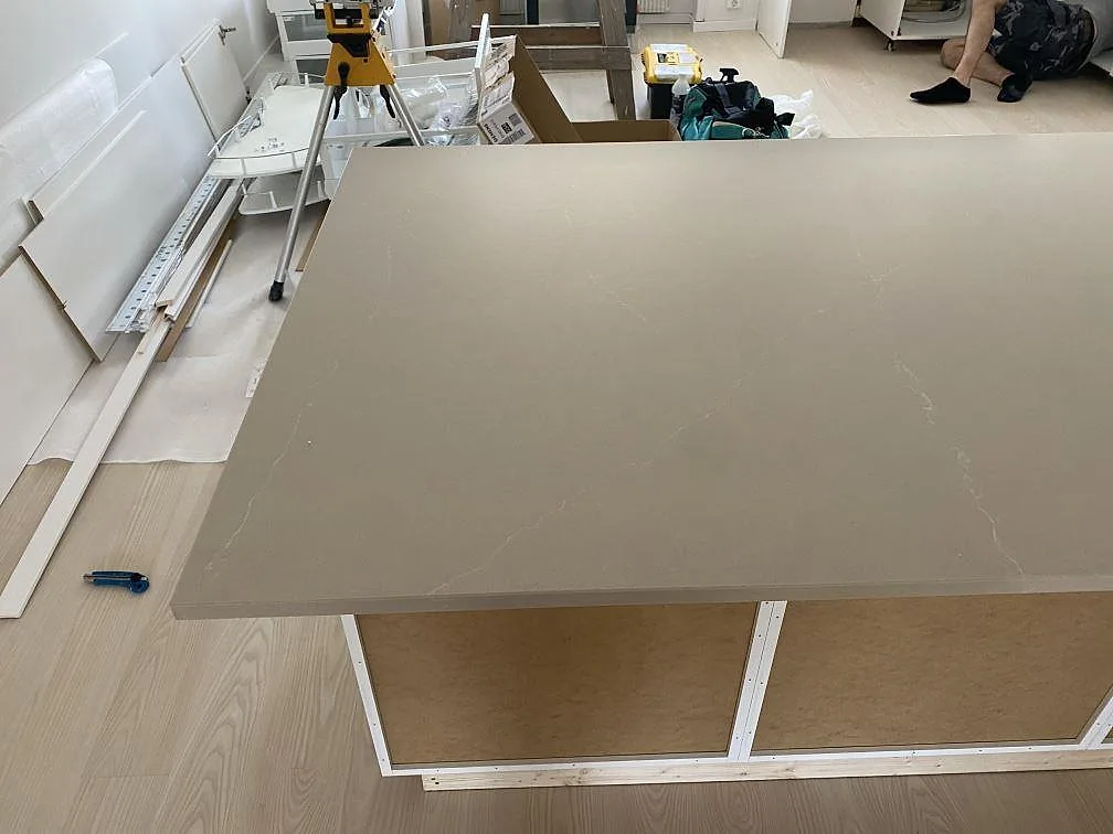 Polerad kompositbänkskiva i Silestone Desert Silver på halvö med monteringsverktyg i köket i Karlshamn.