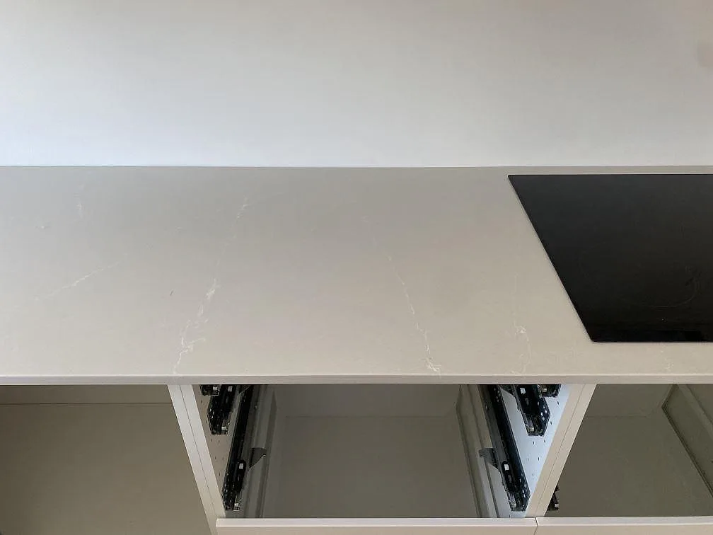 Polerad Silestone Desert Silver bänkskiva med svart induktionshäll och öppna köksstommar i Karlshamn.