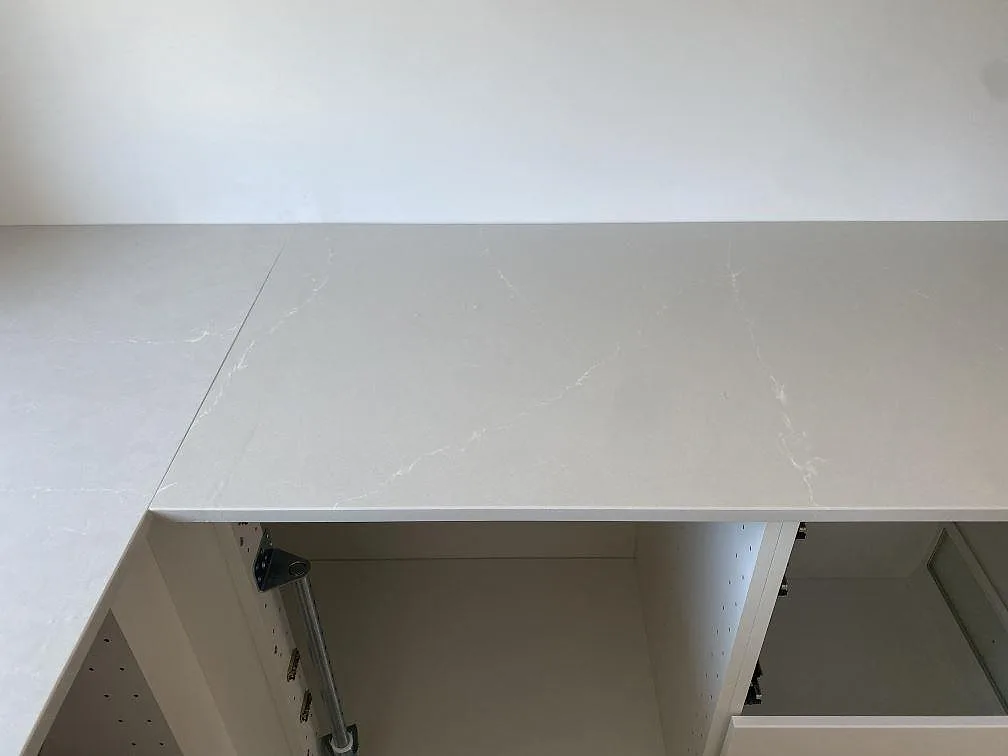 Hörnpassad köksbänkskiva i polerad Silestone Desert Silver med ljus ådring över vita stommar i Karlshamn.