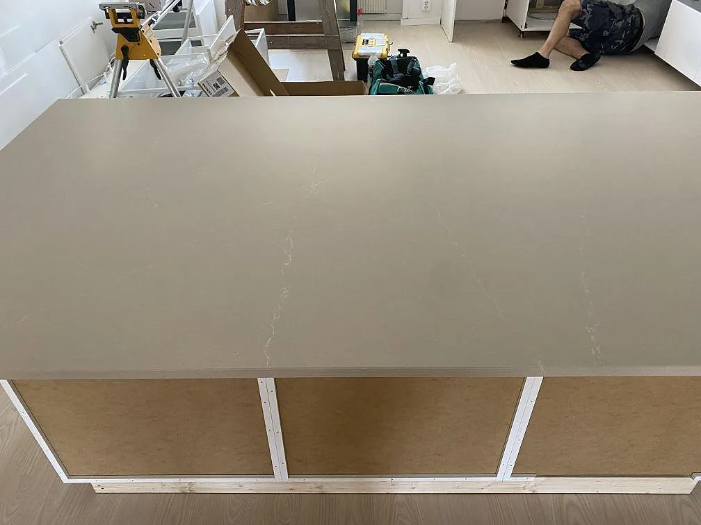 Stor halvö med köksbänkskiva i polerad Silestone Desert Silver och ljus ådring i ett kök i Karlshamn.