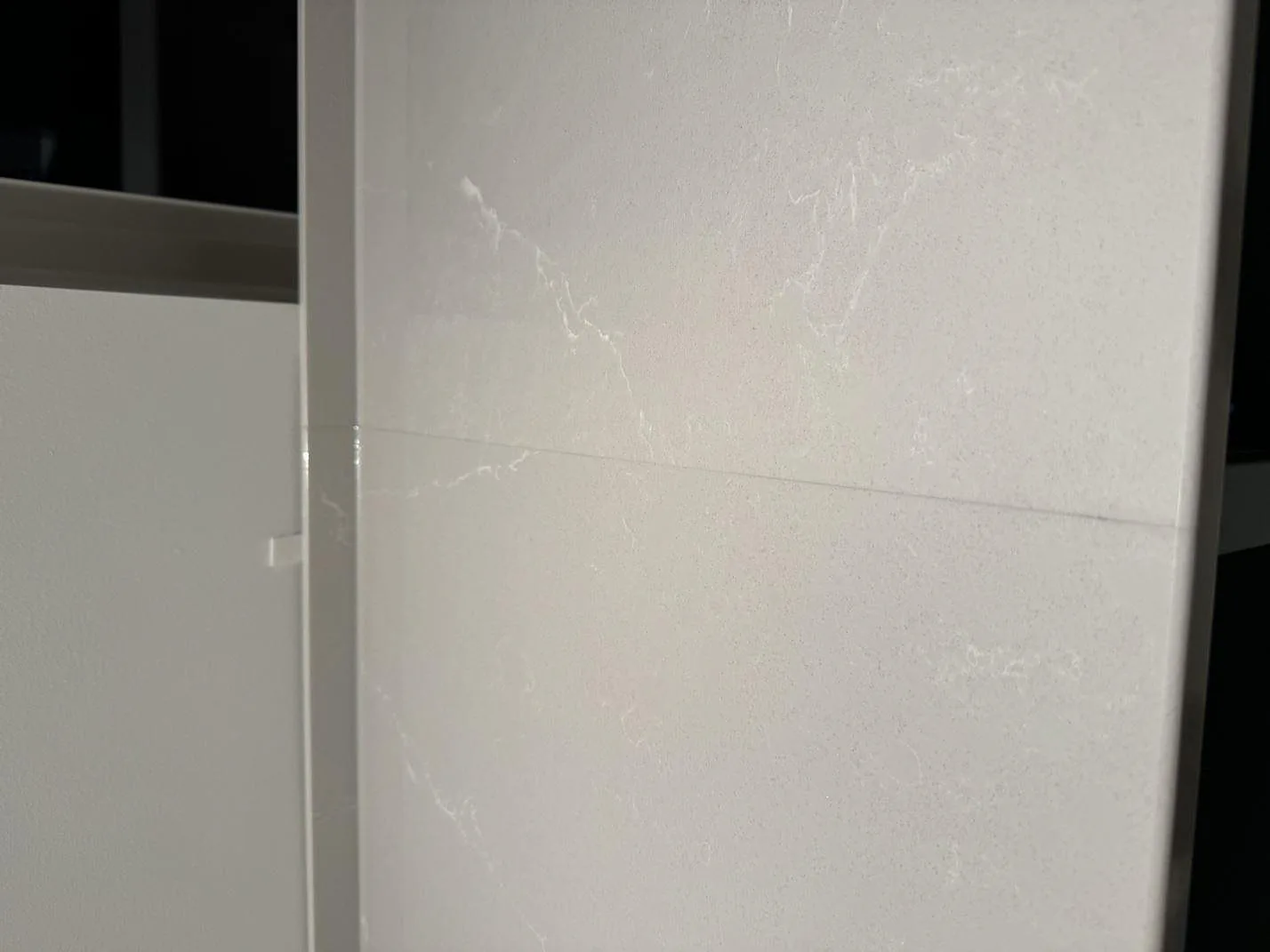Närbild på polerad Silestone Desert Silver med ljus ådring på stänkskyddet i köket i Klagshamn.