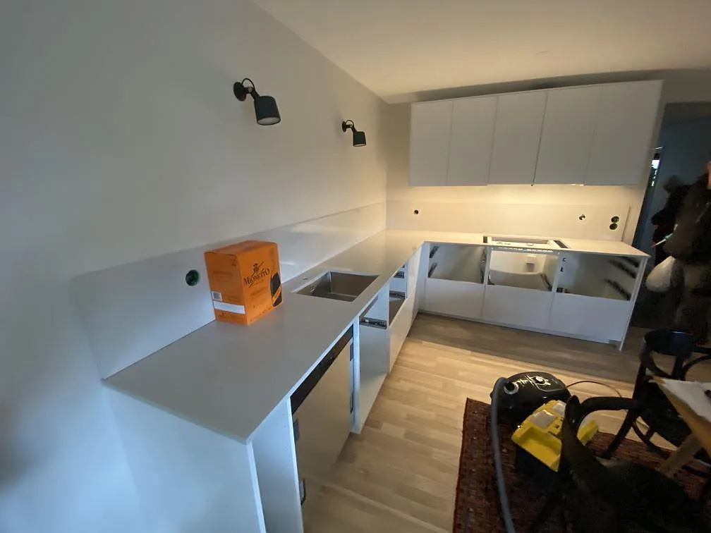Köksbänkskiva i Silestone Desert Silver, polerad, i ett L-format kök i Limhamn med undermonterad rostfri diskho och uppvikt stänkkant, fotograferat under montering.