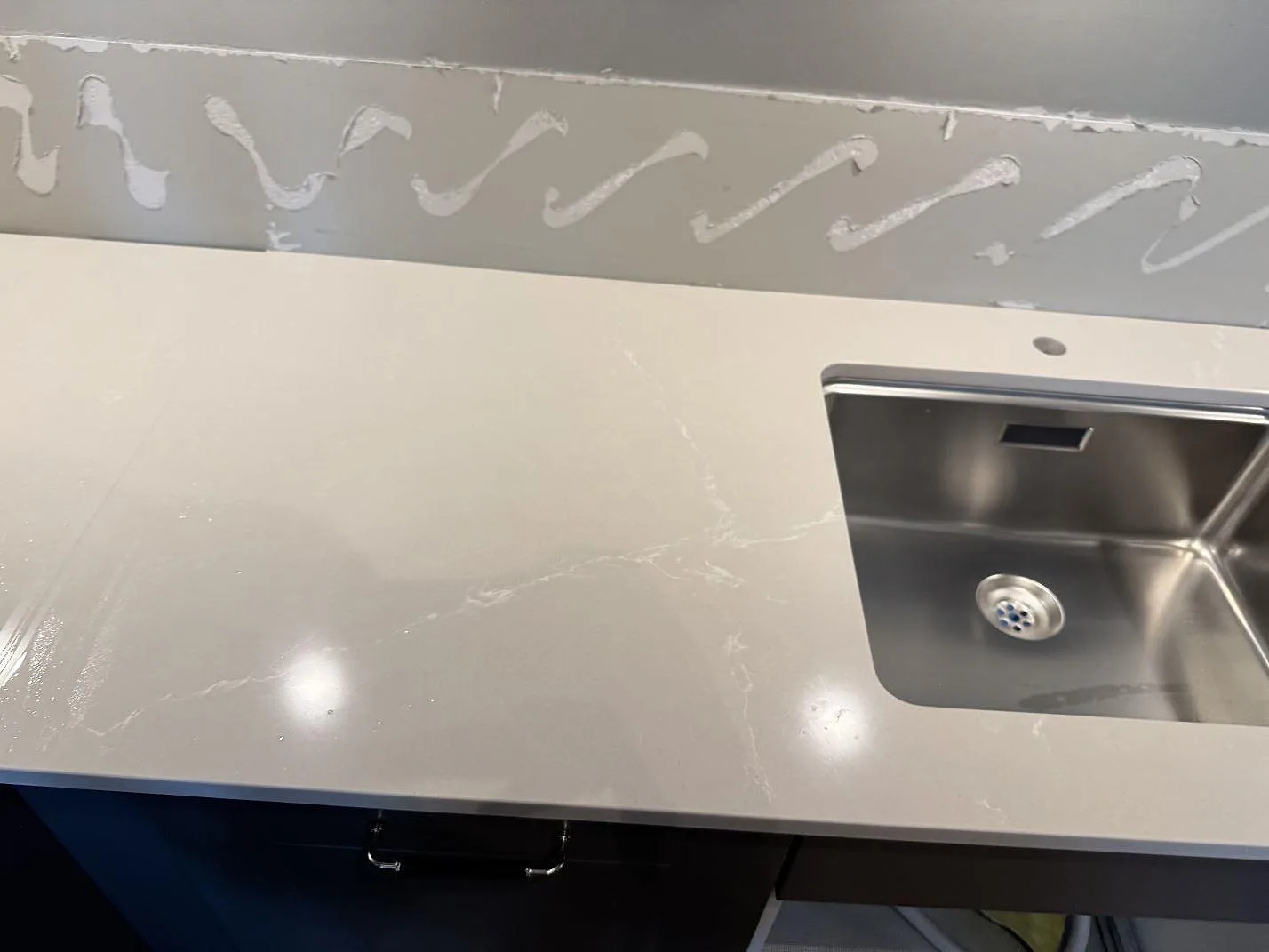 Köksbänkskiva i Silestone Desert Silver, polerad komposit, med rostfri diskho och ljus ådring i Limhamn.