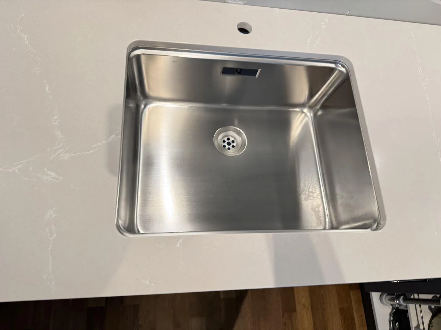 Närbild av polerad Silestone Desert Silver runt rostfri diskho i ett kök i Limhamn.