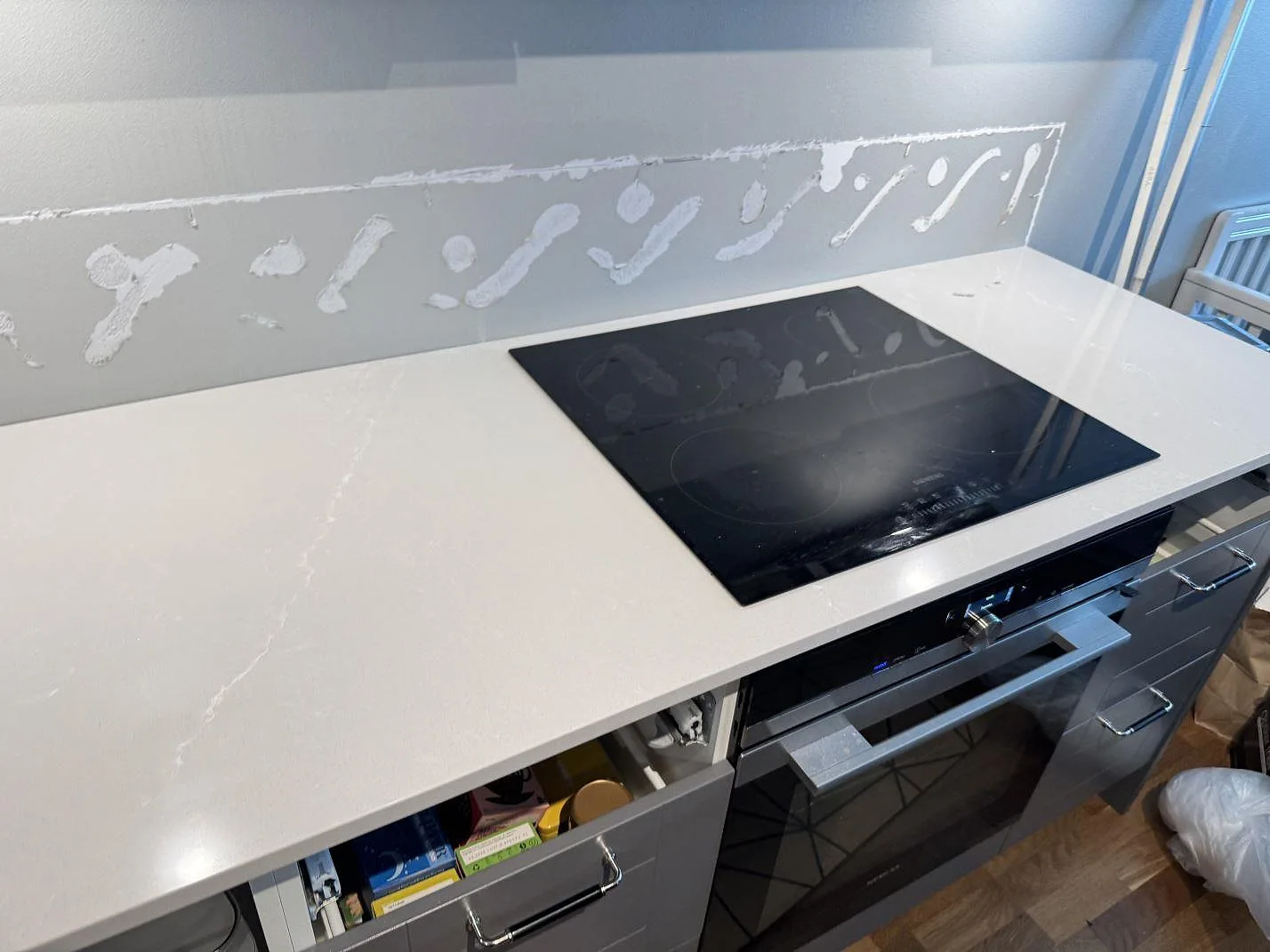 Köksbänkskiva i polerad Silestone Desert Silver med svart häll och ljusa vener i ett kök i Limhamn.