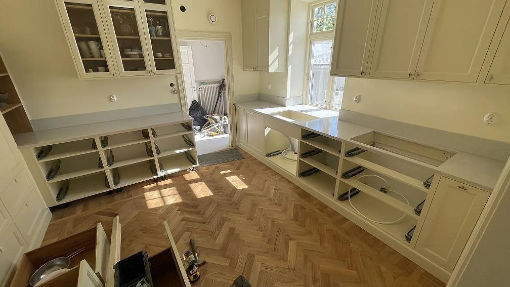 Köksbänkskivor i polerad Silestone Desert Silver, kvartskomposit, med låg stänkkant i ett kök under montering i Limhamn.