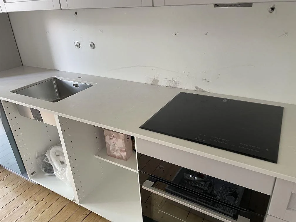 Ljus köksbänkskiva i Silestone Desert Silver, matt komposit, med diskho och häll under montering i Lund.